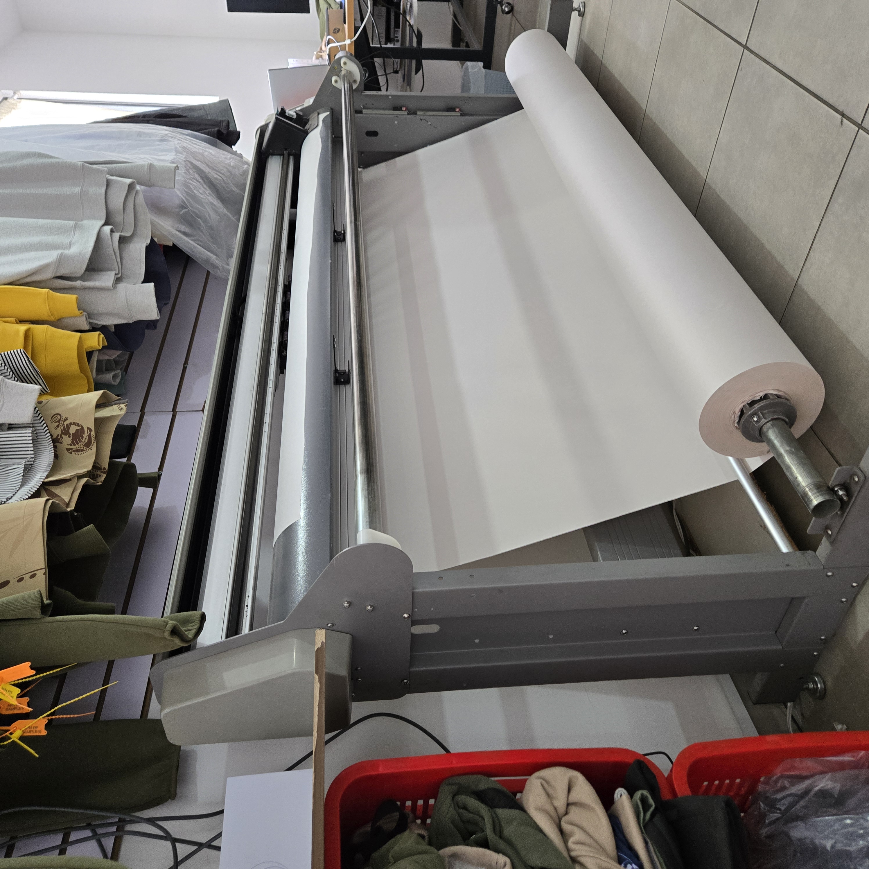 Real fabric-cutting equipment and finished garments in a production workspace